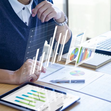 Businessman with virtual reality graphics is deeply reviewing financial reports for a return on investment, ROI, or investment risk analysis.